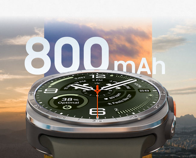 Galaxy Watch Ultra2 in Titanium Silver with a Marine Band in Olive, shown up close facing front and angled upward. The background shows three different skyline and cityscape views at different times of day to demonstrate the large 800 mAh battery capacity.